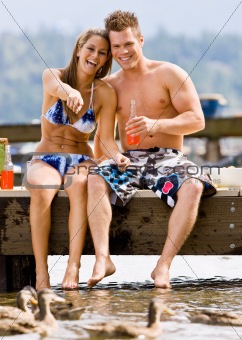 Couple sitting on pier drinking soda
