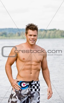 Man in swim trunks wading in lake
