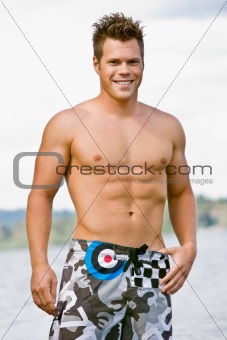 Man in swim trunks near lake