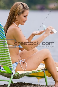 Woman applying sunscreen lotion at beach