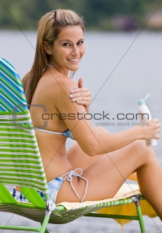 Woman applying sunscreen lotion at beach