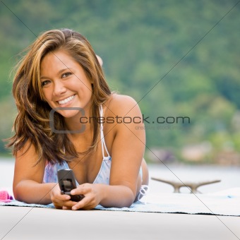 Woman laying on pier text messaging on cell phone