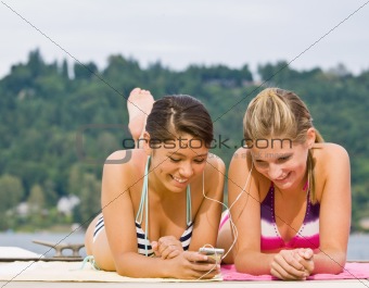 Friends laying on pier listening to mp3 player