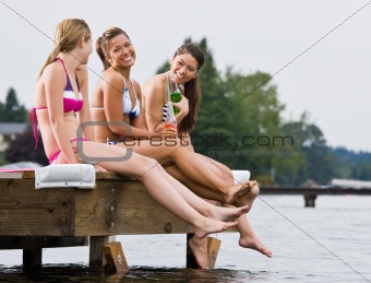 Friends sitting on pier at lake