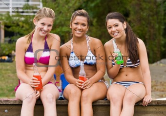 Friends sitting on pier at lake drinking soda