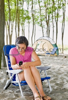 Woman text messaging on cell phone at campsite