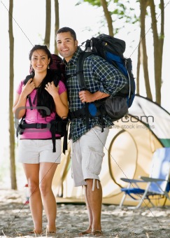 Couple carrying backpacks at campsite