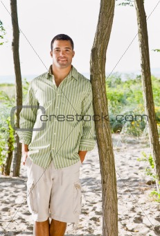 Man leaning on tree at beach