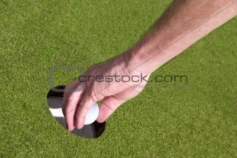Taking golf ball out of hole.