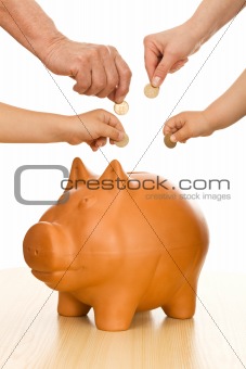 Hands of different generations putting coins in piggy bank