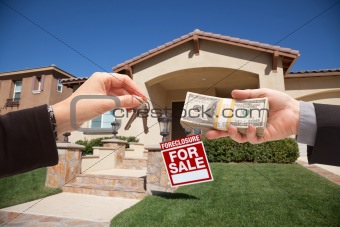 Handing Over Cash For House Keys in Front of House and Foreclosure Sign.