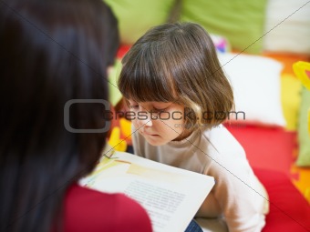 female teacher reading book to little girl