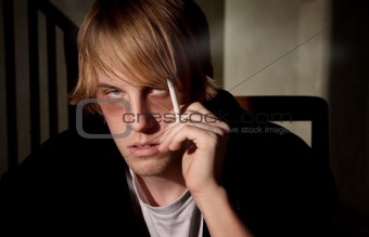 Depressed young man smoking in a tenement hovel