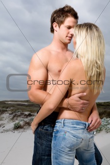 Topless couple embrace on the beach