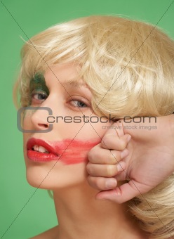 A beautiful girl in a wig. She smears lipstick on the face
