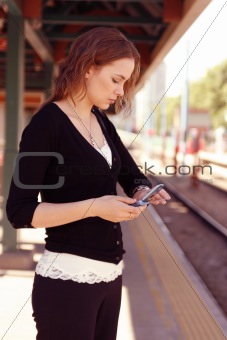 Young woman checks watch while holding cell phone