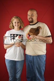 Caucasian male and female holding chickens.