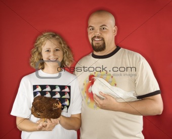 Caucasian man and woman holding chickens.