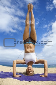 Woman doing yoga on beach.