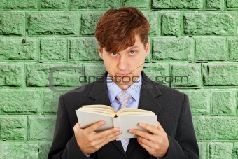 Person reads book on background of green wall