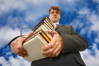 Man with big stack of books against sky