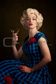 Pretty retro blonde woman in vintage 50s dress with martini