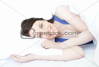 Close-up of a smiling woman waking up slowly against a white background