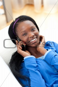 Bright woman listening music with headphones lying on a sofa in the living-room