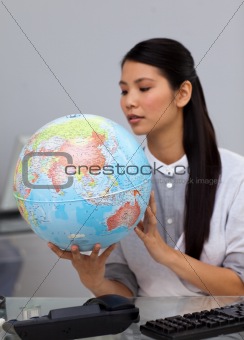 Concentrated businesswoman looking at a globe 
