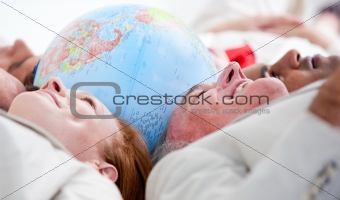 Smiling business people lying around a globe
