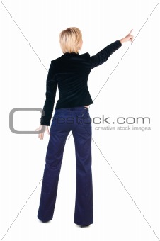 Young woman points at wall. 