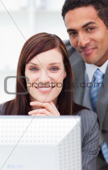 Two smiling colleagues working at a computer