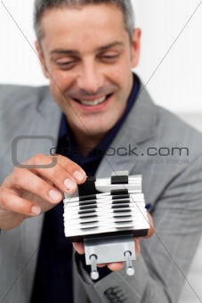 Charming businessman consulting a business card holder 