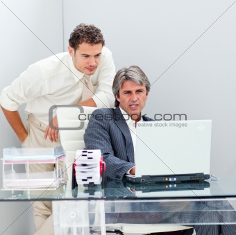 Confident manager helping his colleague work at a computer