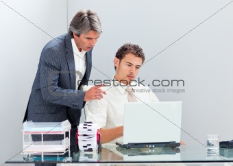 Concentrated manager helping his colleague work at a computer