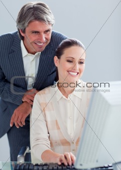 Caucasian manager helping his colleague work at a computer