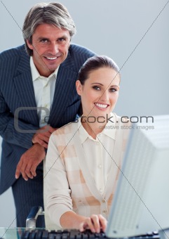 Mature manager helping his colleague work at a computer