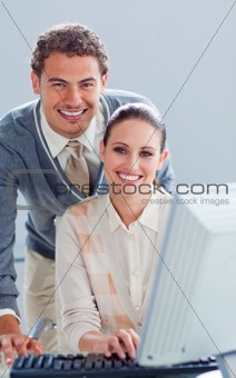 Handsome businessman helping his colleague work at a computer