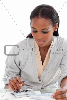 Charming businesswoman using a calculator at her desk