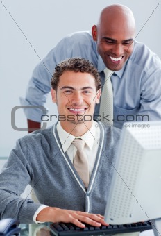 Two attractive businessmen working at a computer