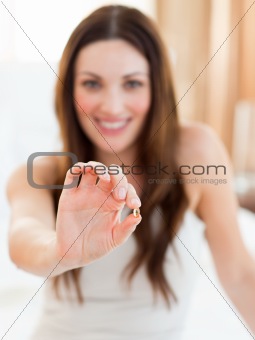 Smiling woman taking a pill sitting on bed