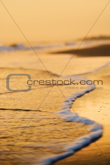 Waves lapping on beach at sunset.