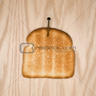 Slice of toast nailed to wood. 