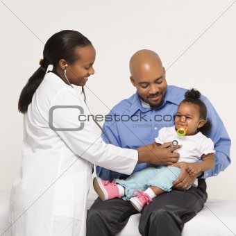 Father holding baby for pediatrician to examine.