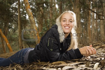 Caucasian woman lying in forest.