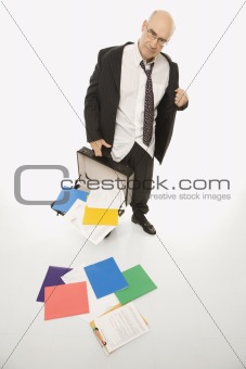 Businessman losing papers from briefcase.