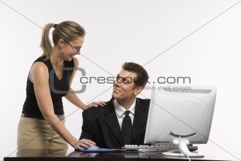 Woman looking over man's shoulder and using computer.