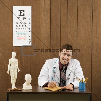Male doctor at desk writing.
