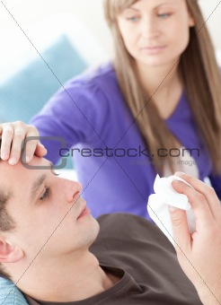 Caring woman taking her sick husband's temperature in their bedroom