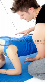 Brunette woman working out assited by her personal trainer